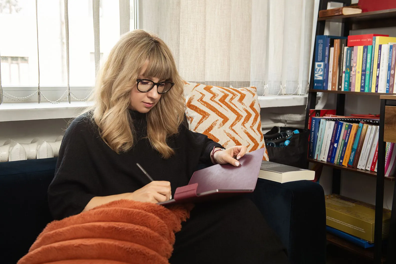 Andreea Negruti scriind într-un caiet, pe canapeaua din cabinet
